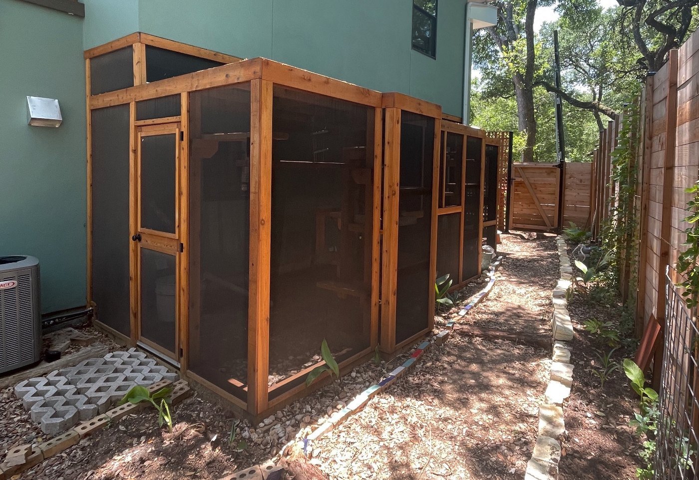 A long cedar Signature catio running down the side yard of a home, shaped around the pathway and planting beds