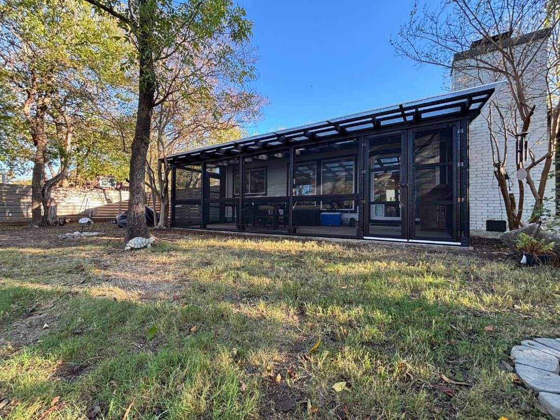 A Signature catio with a black-stained frame and slatted roof, built the length of the house