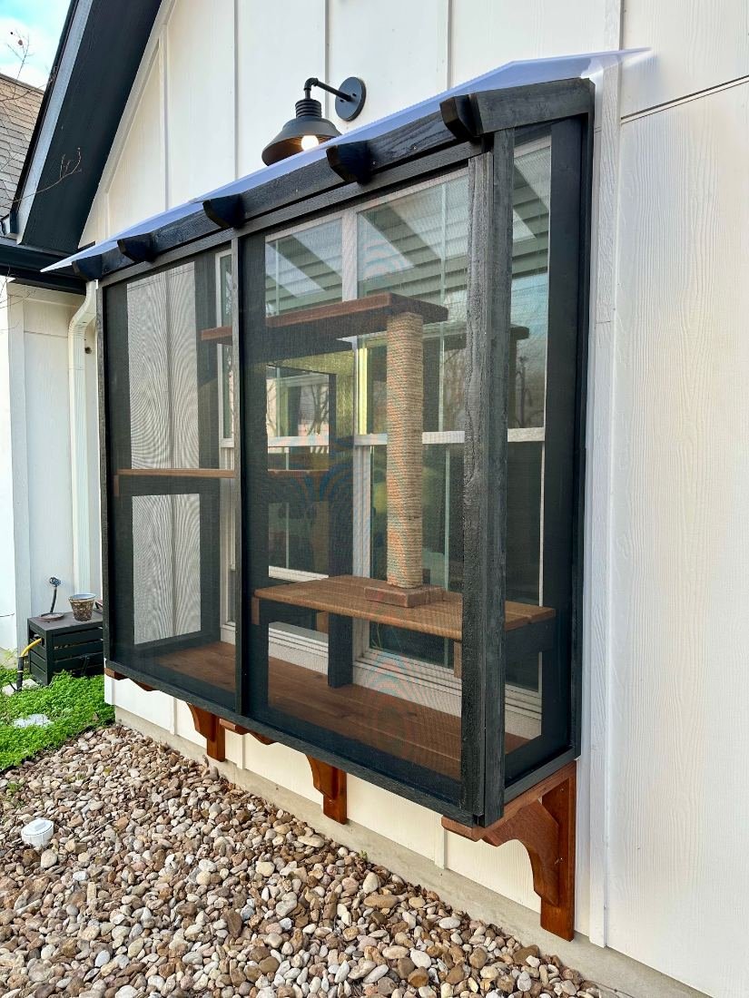 Window catio the width of the window itself, black frame on stained cedar corbels with a polycarbonate roof, seen straight on