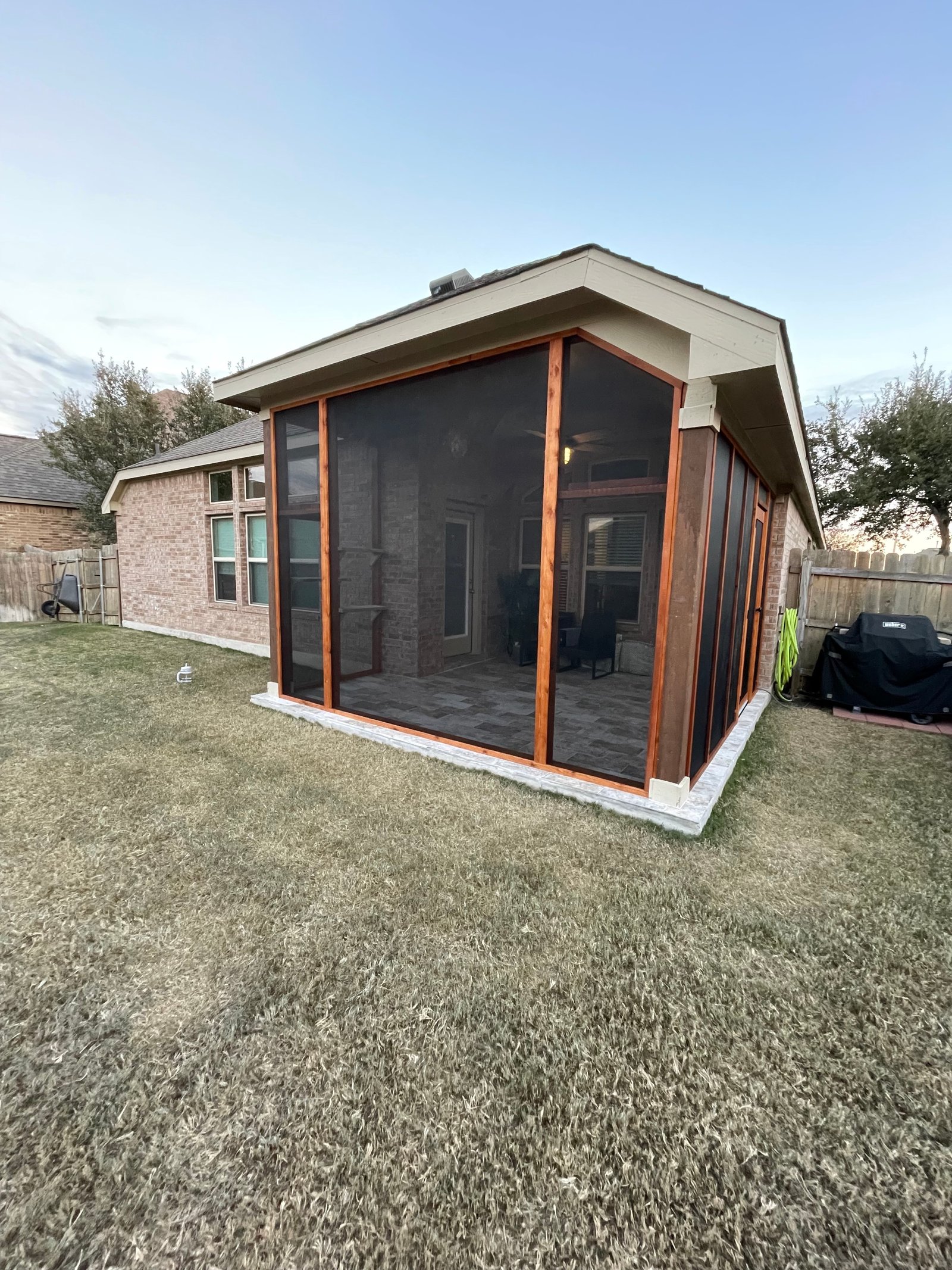 An odd-shaped three-sided porch screened in cedar, cat shelves following the angled walls