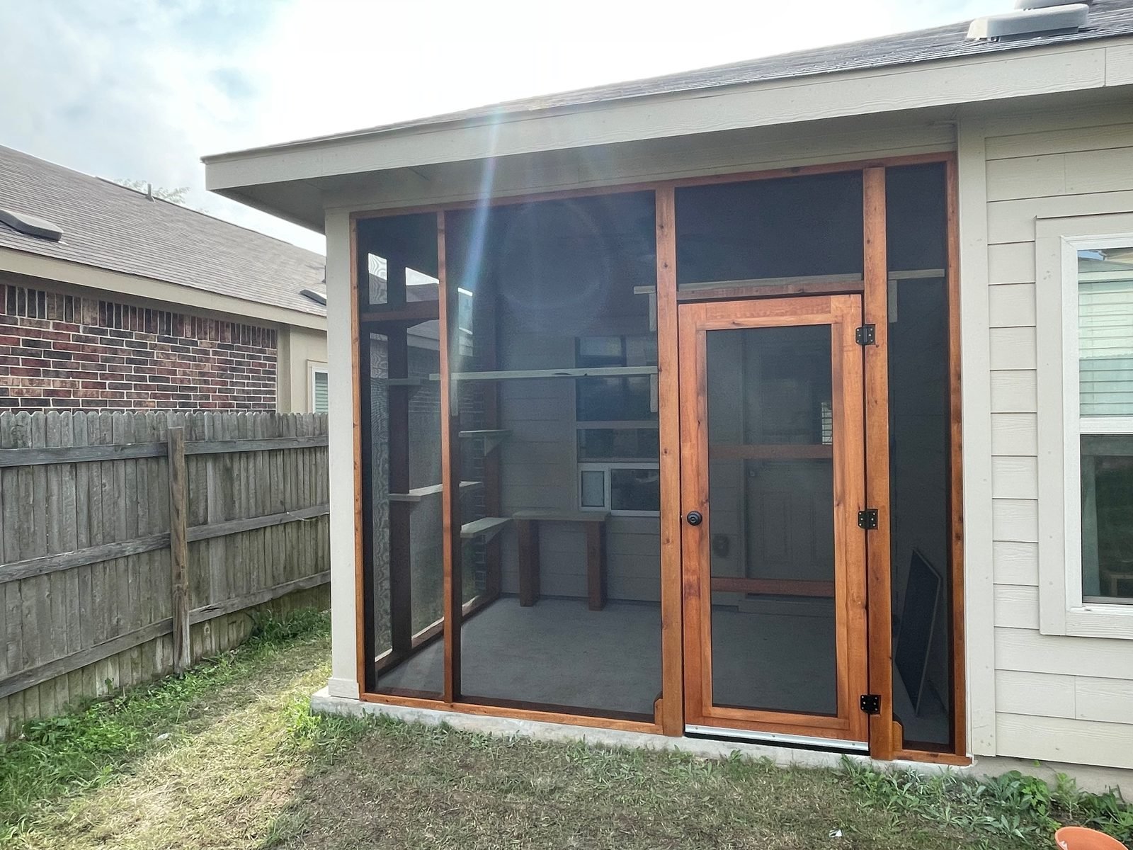 The same patio screened in cedar with a handmade screen door and climbing shelves