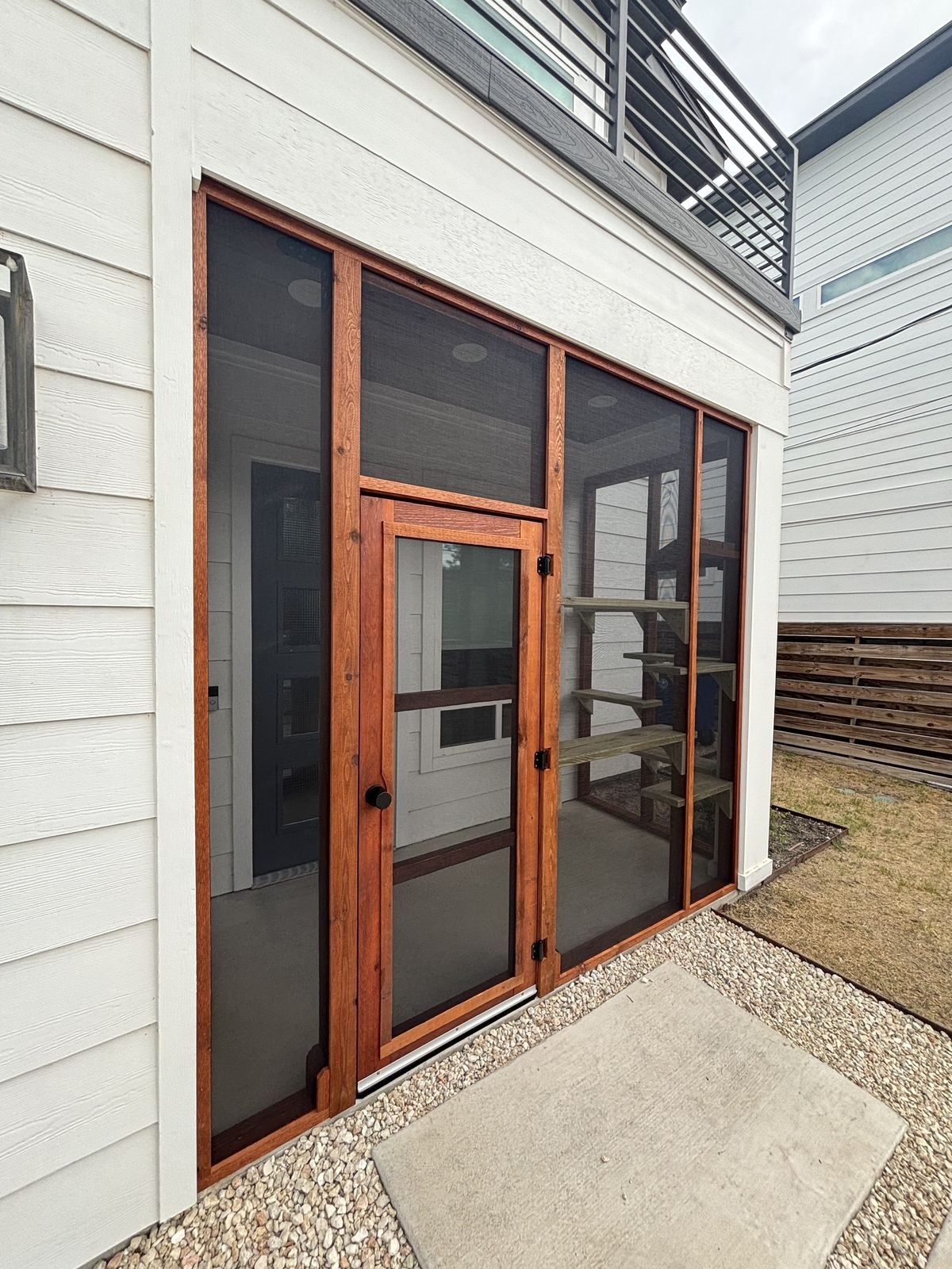 Finished porch catio with cedar shelving and a handmade screen door